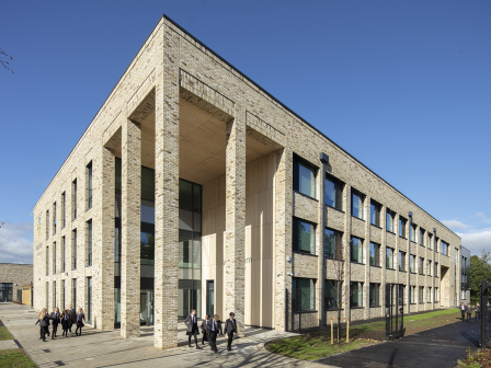 Long-shot of Woodham Academy, showing off the profile of the academy with children walking along the path