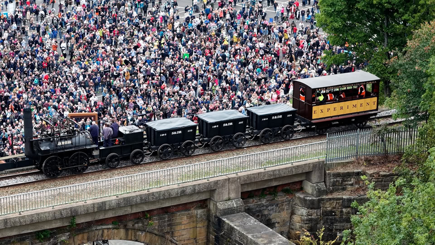 A locomotion crossing the Skerne Bridge as crowds watch from below
