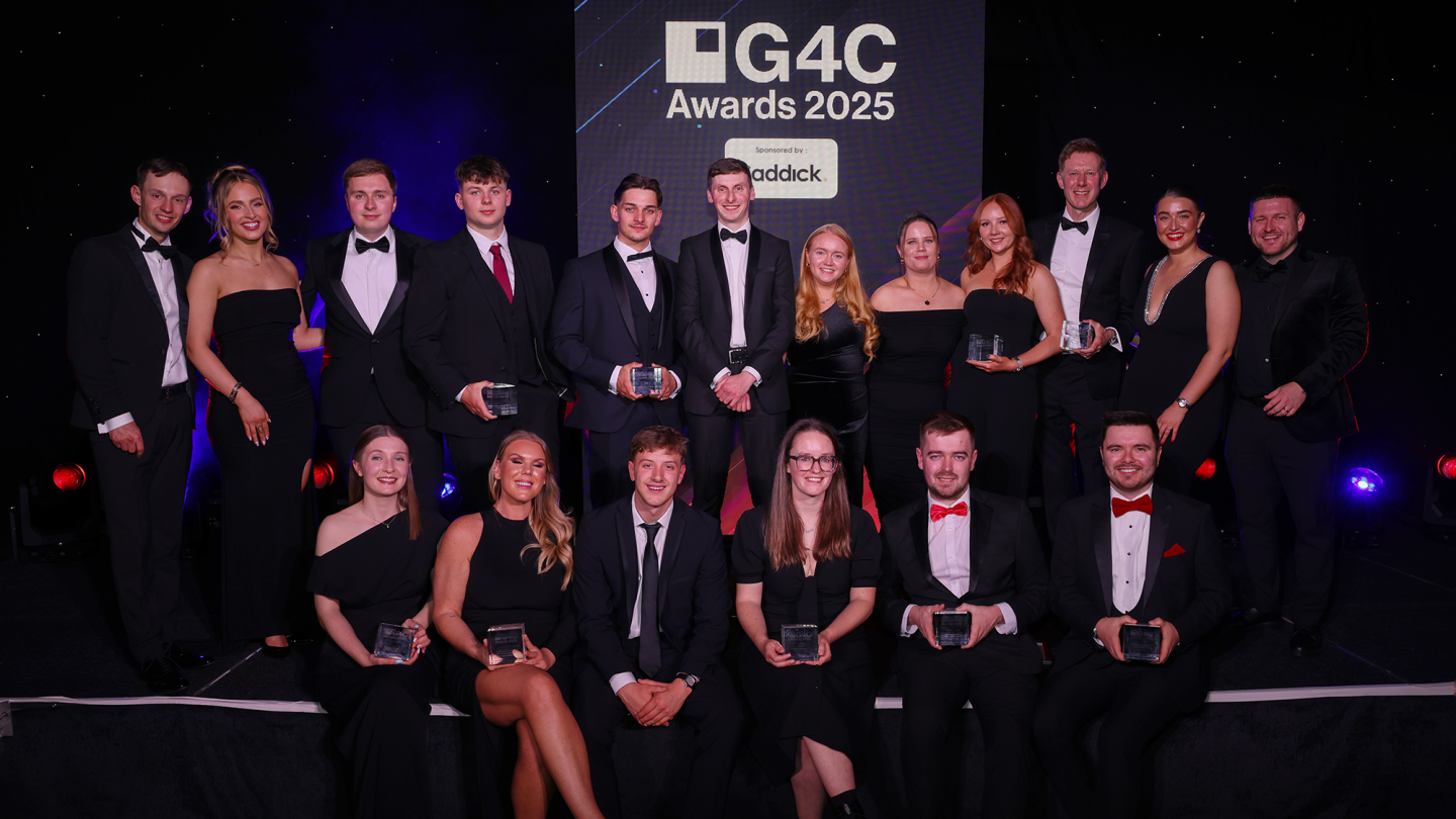 A group of people in black tie stand and sit holding cube-shaped glass awards