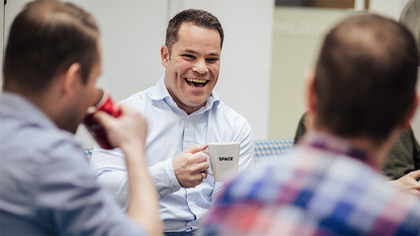Grant Bramwell of SPACE Architects laughs while holding a SPACE branded mug