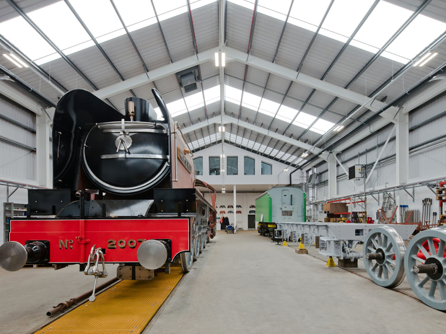The inside of a train warehouse, with a old-fashioned steam train