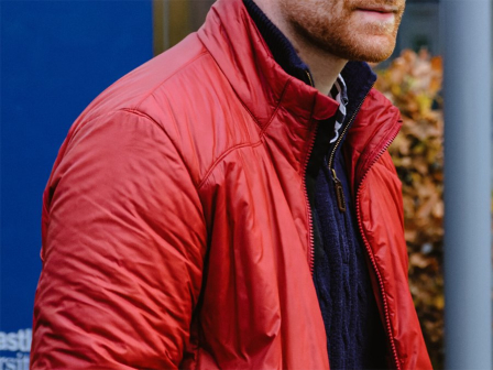 A man in a blue jumper and red jacket joins in conversation