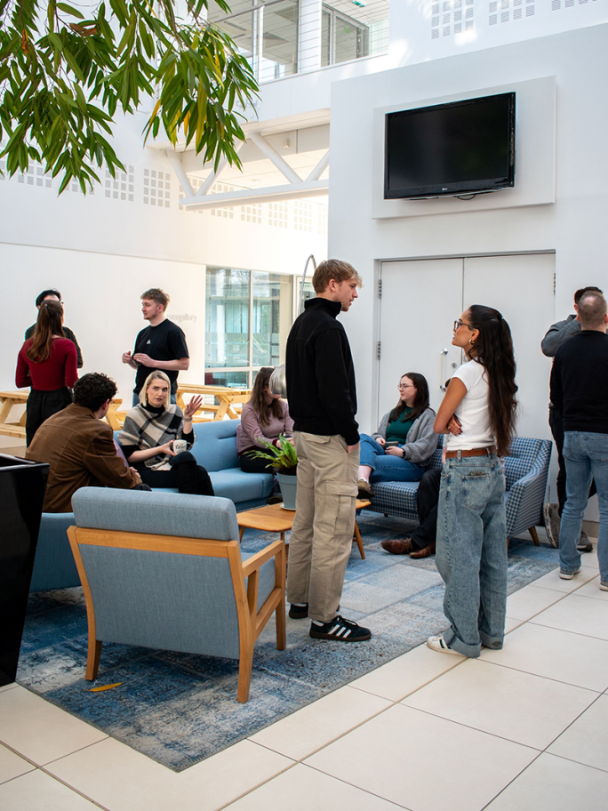 A closer up image of SPACE Architects members sitting and standing while talking over coffee