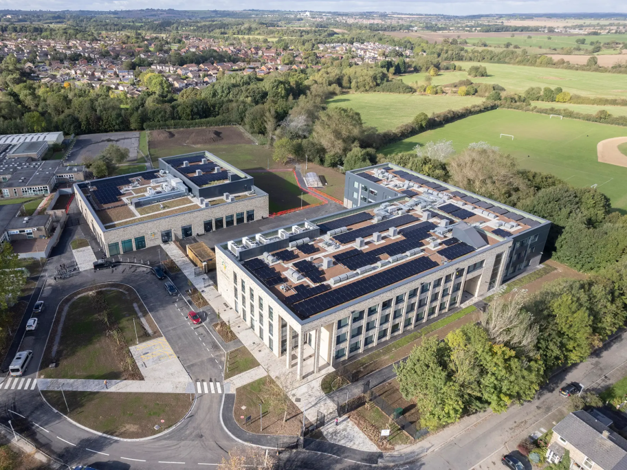 A birds-eye aerial view of Woodham Academy, showing Solar Panels on the roof and surrounding countryside