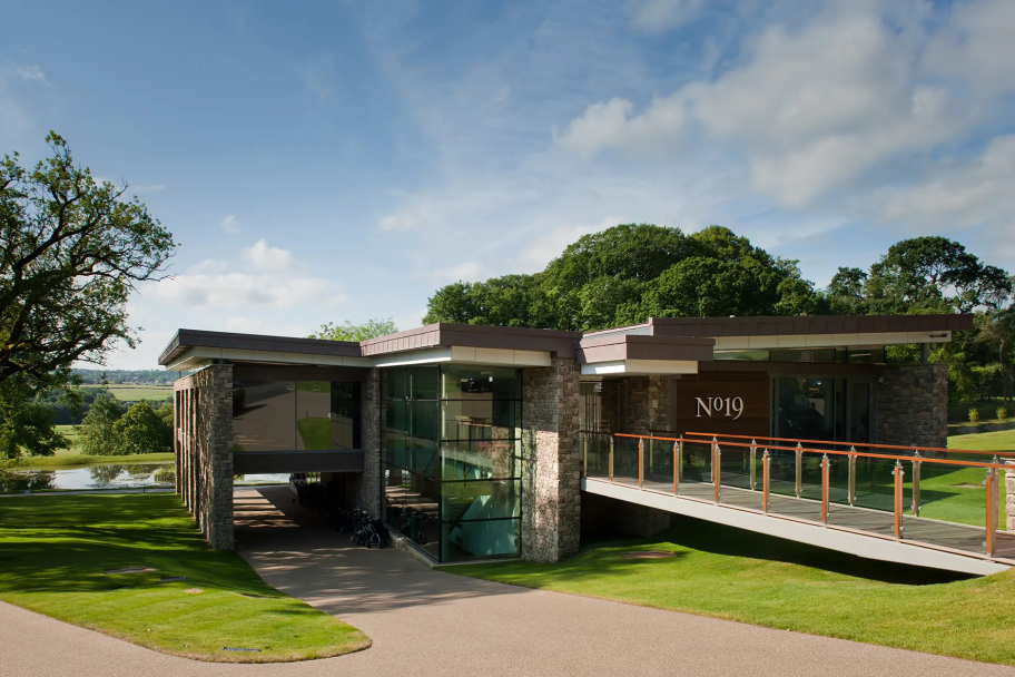 A view of the rear entrance to the clubhouse, with a walk bridge and surrounding trees