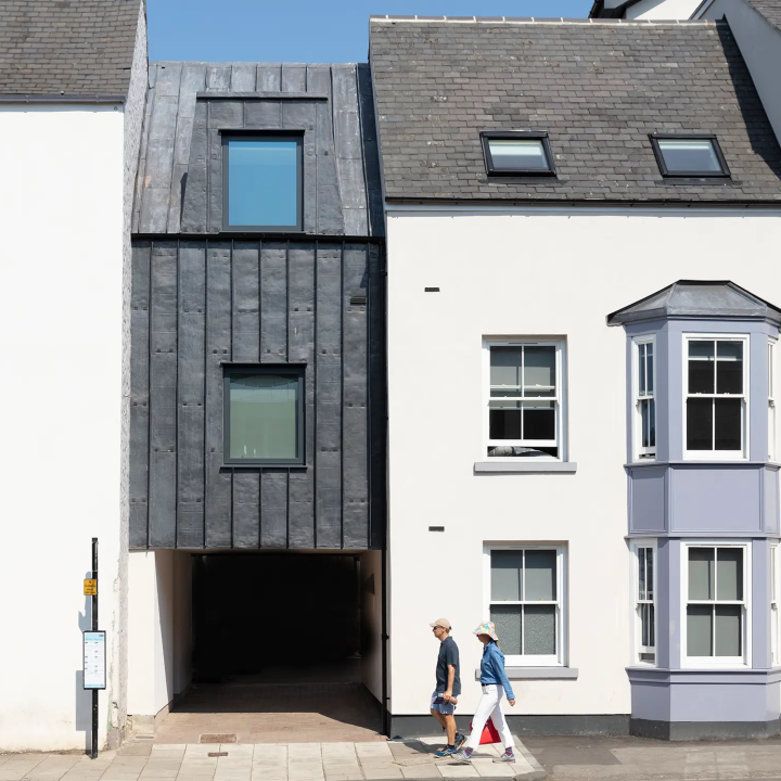 Locals walk past the accommodations, with the unique black façade contrasting the white paint
