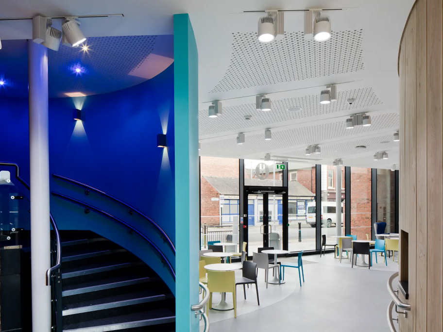 A stairwell leading down to a social area with tables and chairs