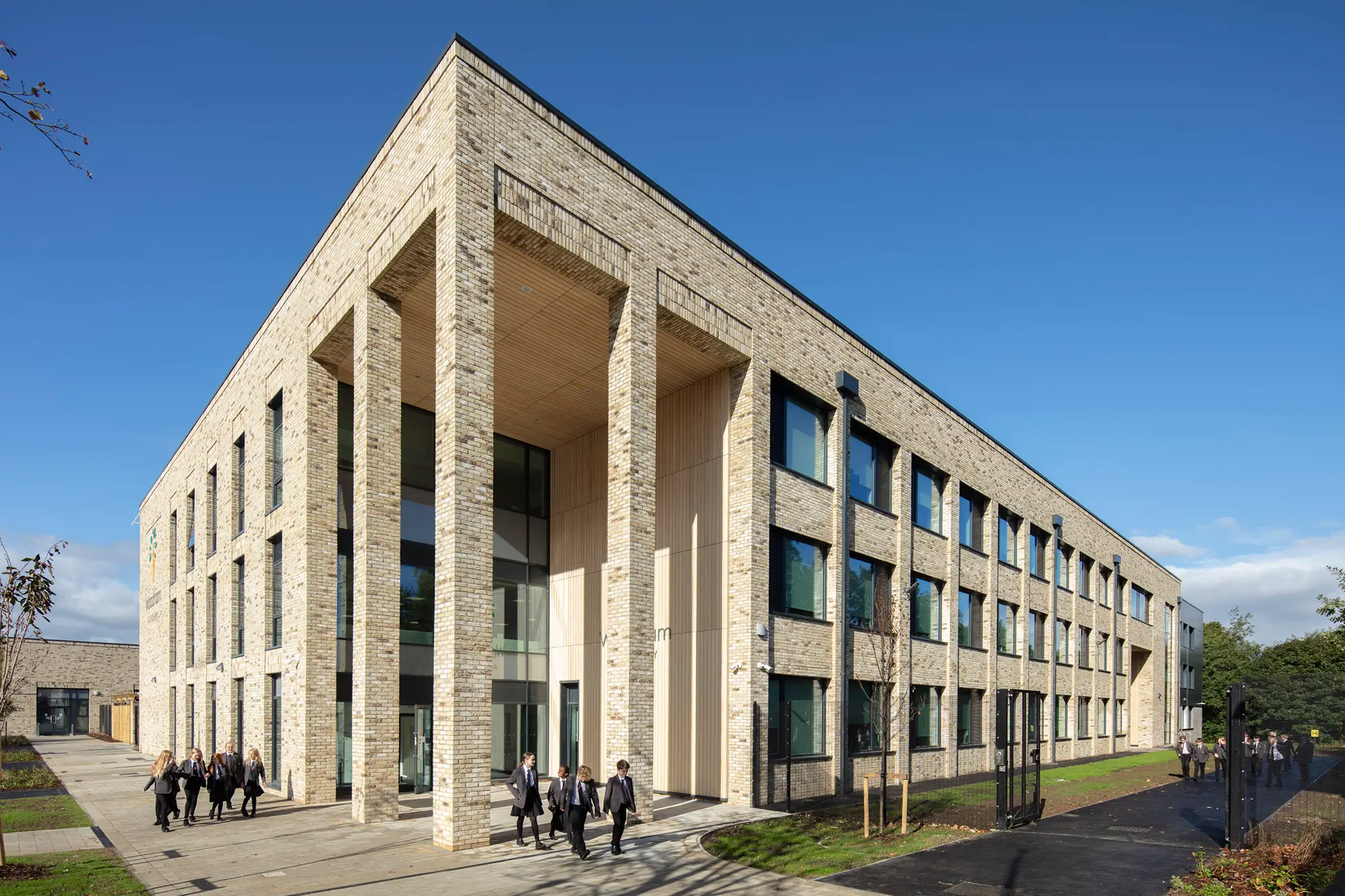 Long-shot of Woodham Academy, showing off the profile of the academy with children walking along the path