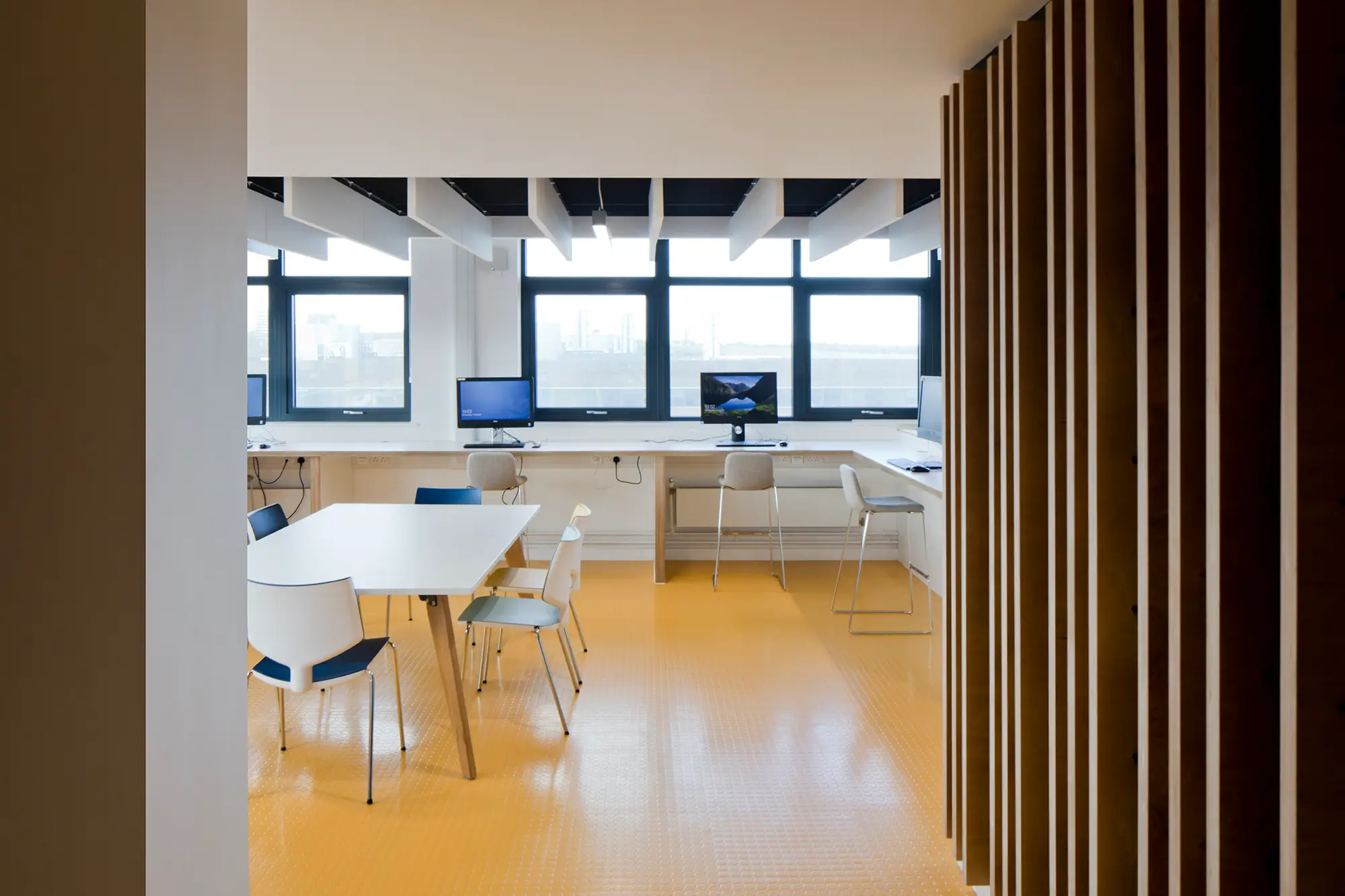 Inside a computer and collaborative study space with yellow tiled floors and acoustic ceiling panels