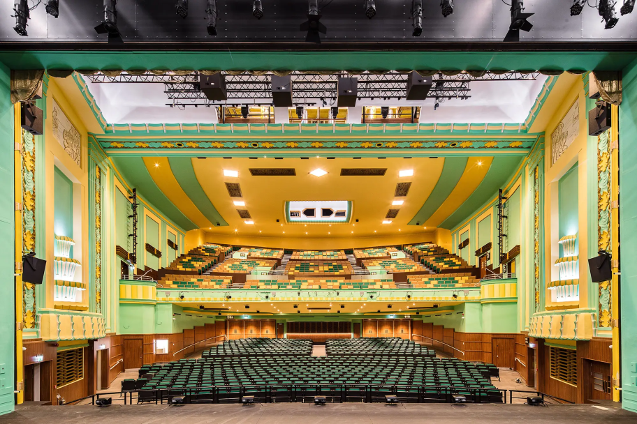 Inside the Stockton Globe Auditorium with yellow and green assets combined with wood panelling