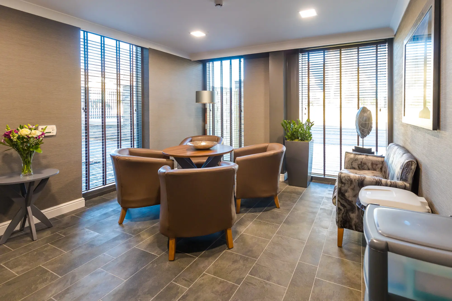 Inside a living space in Bede House, with a small table and dining chairs, as well as a sofa and bins