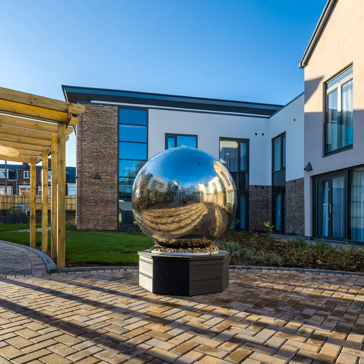 A spherical silver sculpture in the garden area outside Bede House