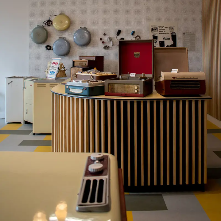Inside the 1950s electronics shop, which old-fashioned record players, ovens, and other electrical devices