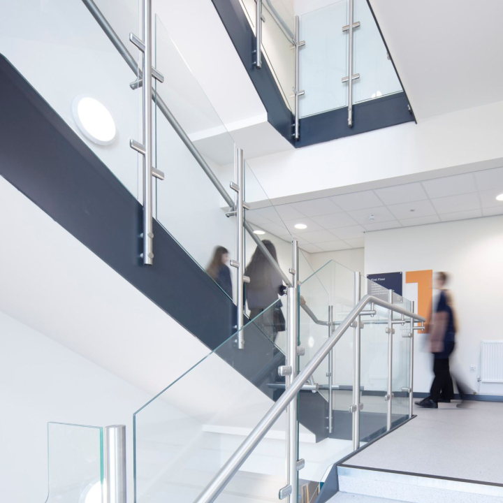 Woodham Academy dining halls, with large logo on the wall and several long benches for students to sit at