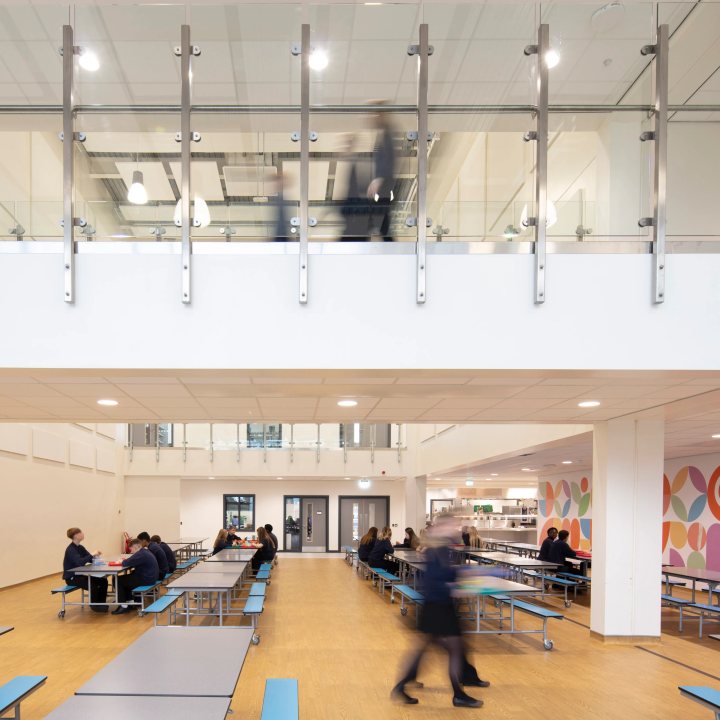 Inside a classroom, there are students wearing dark grey uniforms working at desks