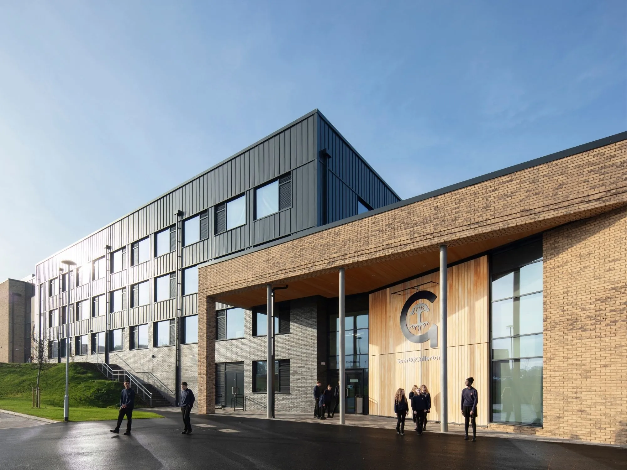 Long-shot of Callerton Academy, showing off the profile of the academy with children walking along the path