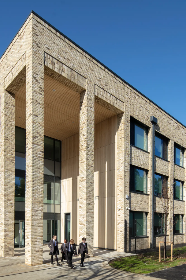 Long-shot of Woodham Academy, showing off the profile of the academy with children walking along the path