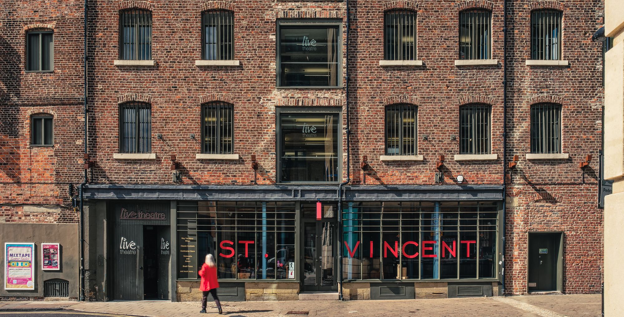 Women in red walking past the Live Theatre facade in Newcastle upon Tyne